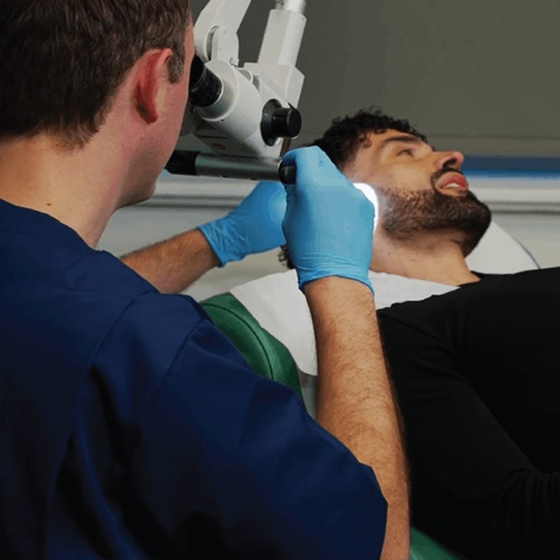 A clinician using a sterile single-use tip under the microscope