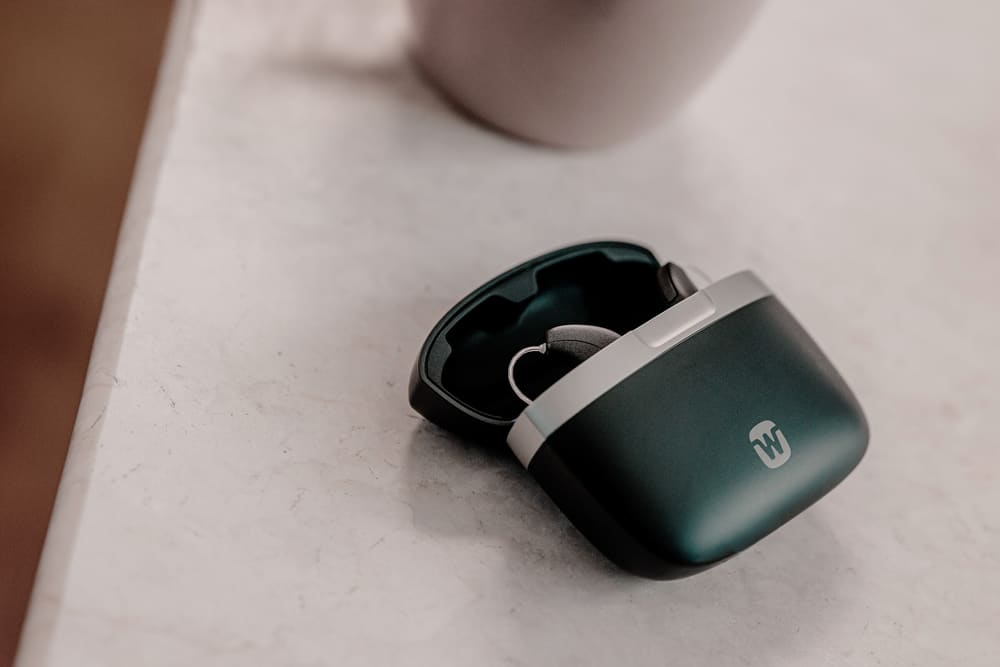 Widex Allure AI hearing aids in their portable charger